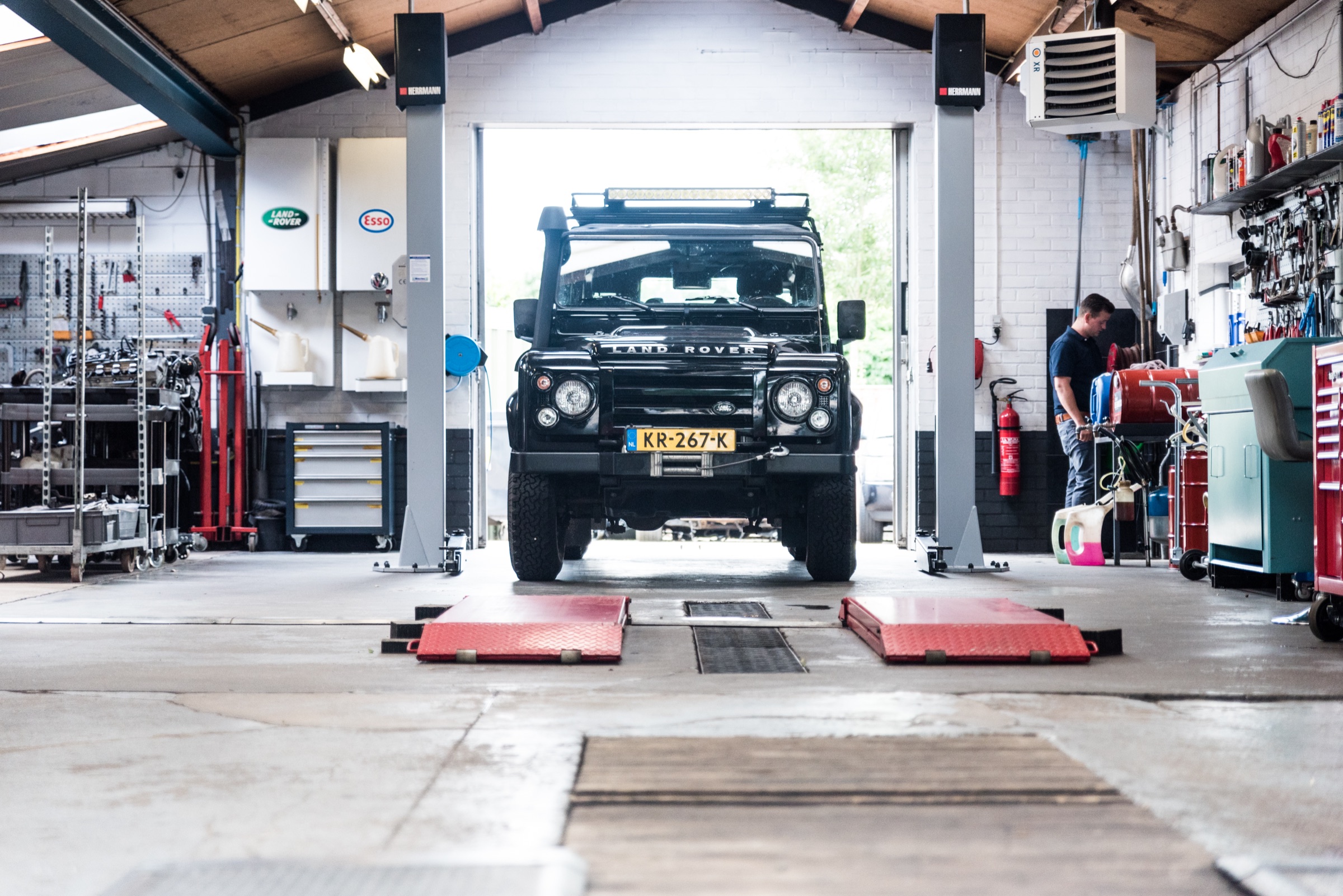 Een zwarte Land Rover Defender op de brug in de werkplaats