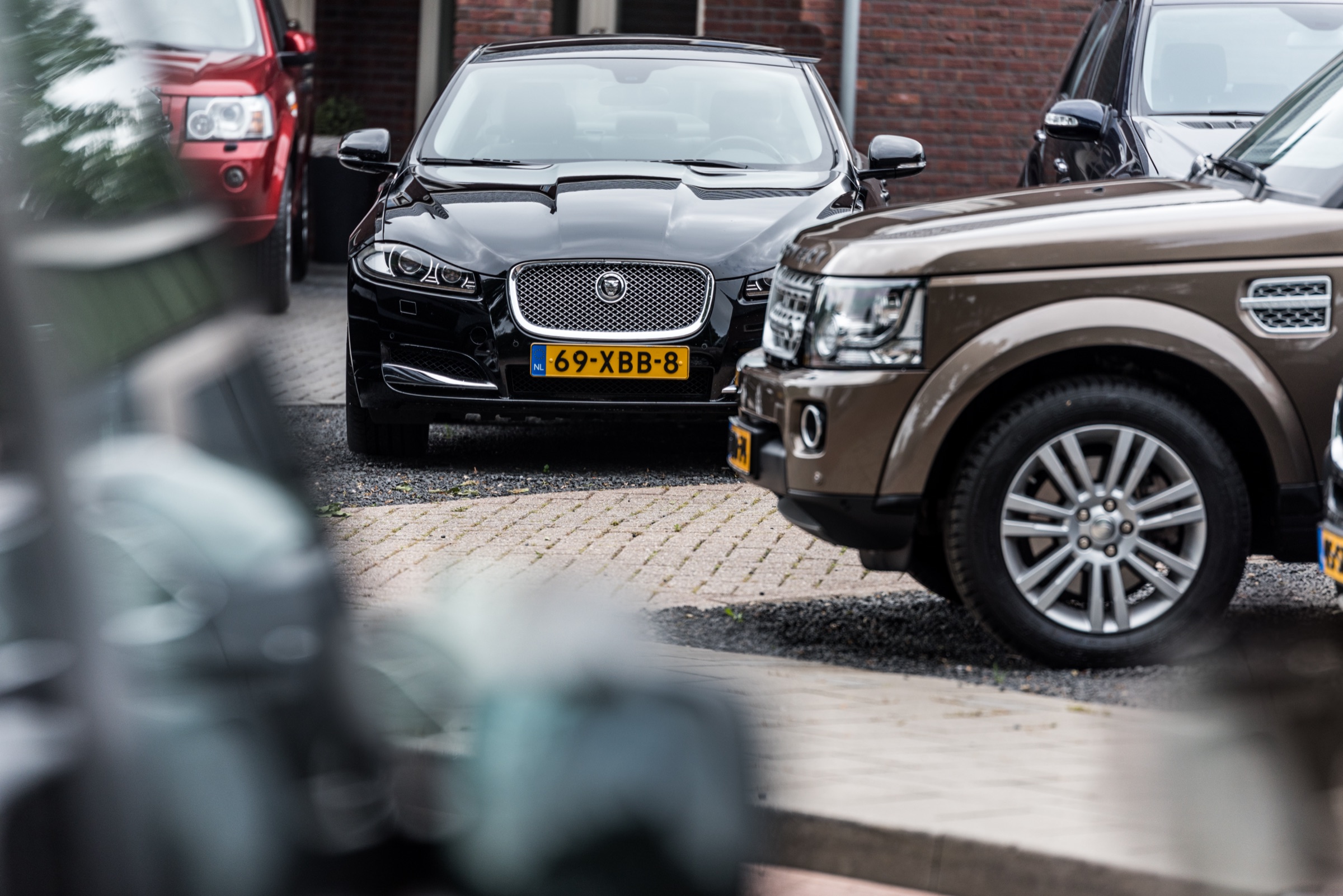 Een zwarte Jaguar XF en een bruine Land Rover Discovery op het terrein