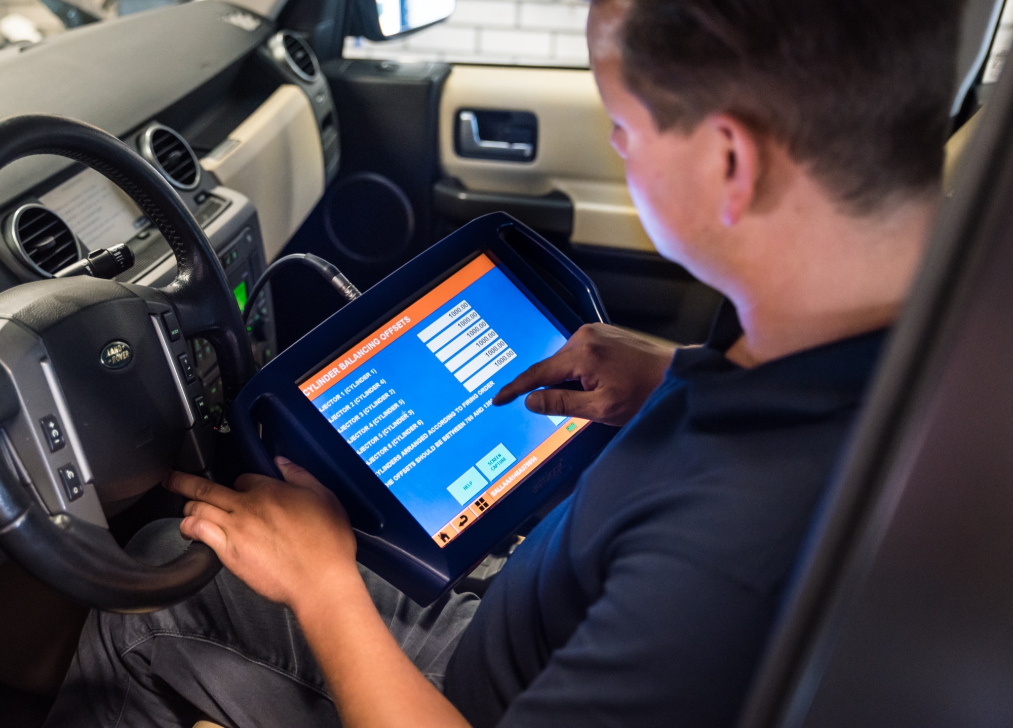 Monteur leest met een diagnosetablet de injectoren van een Land Rover Discovery uit