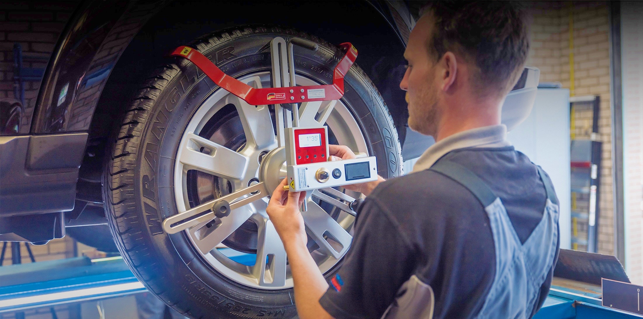 Monteur met uitlijnapparatuur op het wiel van een auto