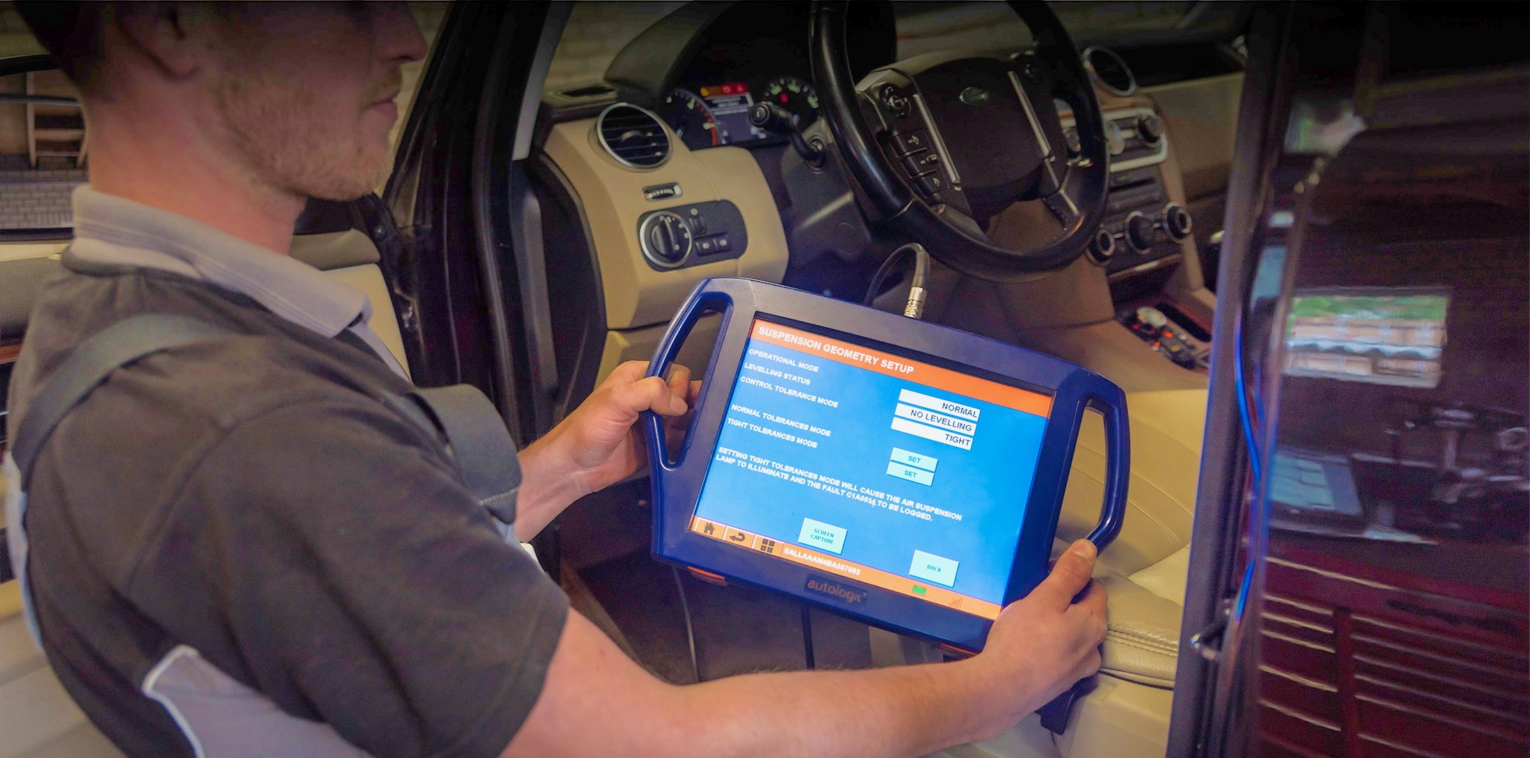 Monteur met een diagnosetablet achter het stuur van een Land Rover
