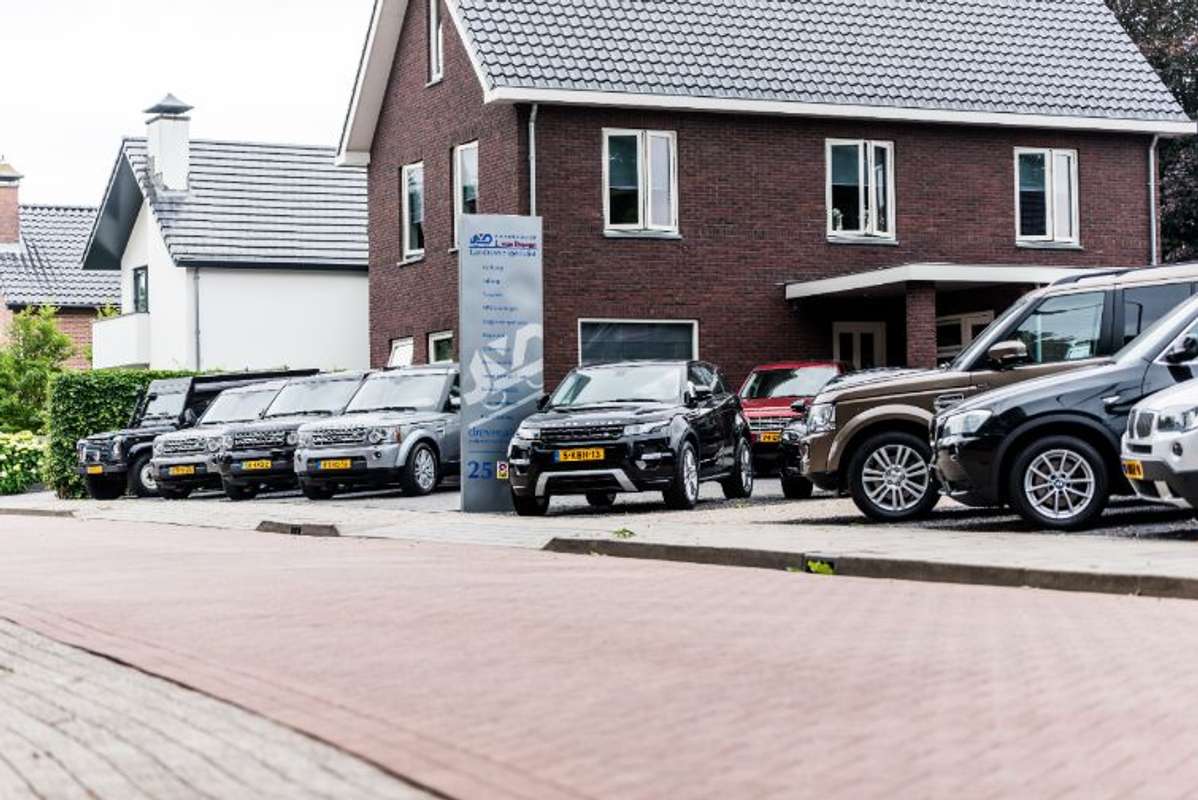 Het pand van Autobedrijf J. van Dreven met de reclamezuil en een rij Land Rovers en Range Rovers
