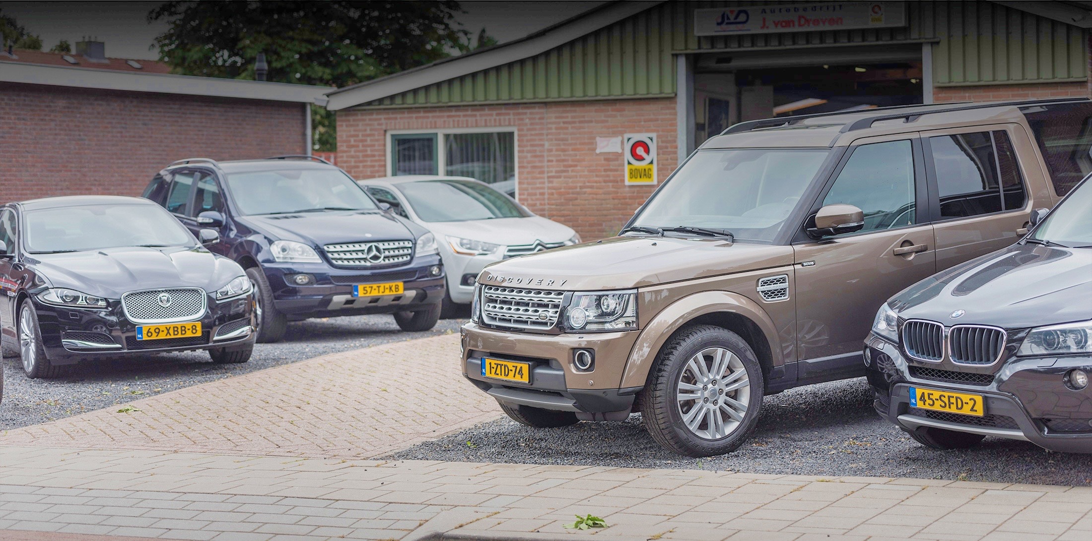 Een bruine Land Rover Discovery op het terrein van Autobedrijf J. van Dreven
